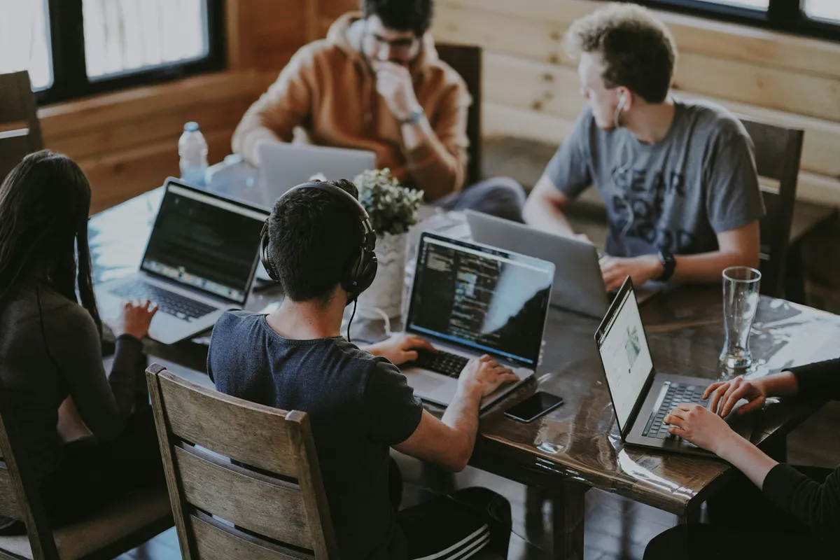 Engineering team collaborating on laptops around a shared table during an AI delivery sprint